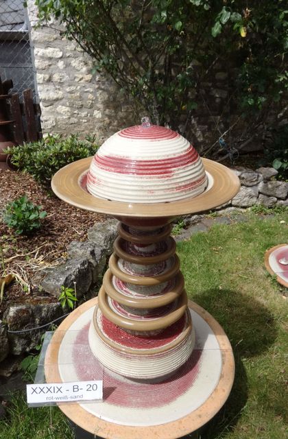 Terrassenbrunnen Modern aus winterfester Keramik mit gerillter Halbkugel und kaskadenförmiges Abtropfen über Teller, dezente Akustik rot-weiß-sand