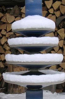 Moderner Gartenbrunnen aus winterfester Keramik mit gerillter Säule und 4 Kegeln im Winter