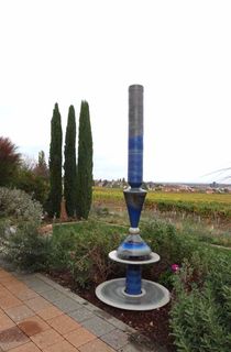 Lebendiges Wasser auf Keramikbrunnen winterfest im Garten mit Lichtreflexen über zwei farbige Kegel, dezente Akustik