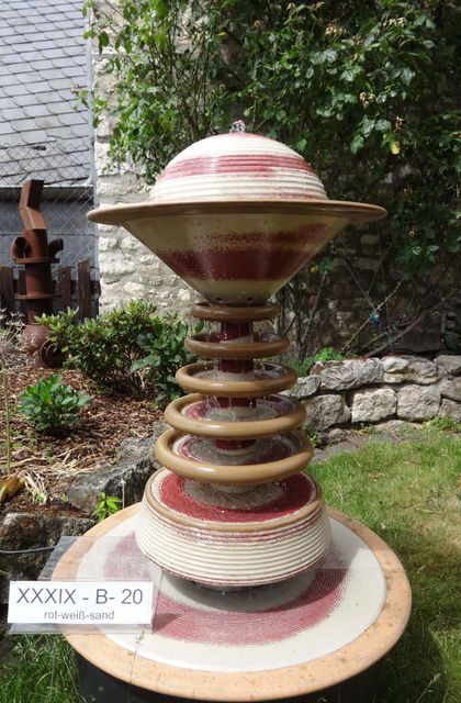 Moderner Gartenbrunnen aus winterfester Keramik mit gerillter Halbkugel und kaskadenförmiges Abtropfen über Teller, dezente Akustik