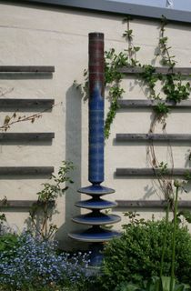 Moderner Gartenbrunnen aus winterfester Keramik mit gerillter Säule und Lichtreflexen über vierfarbige Kegel, sehr leise